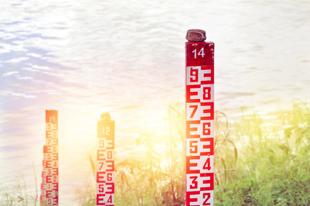 water level marker with numbers at a river in sunlight.の写真素材
