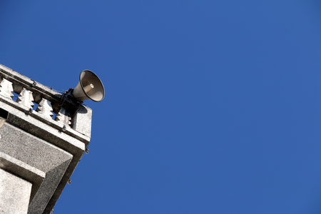 loudspeakers on a rooftop of church on blue sky with copy spaceの写真素材