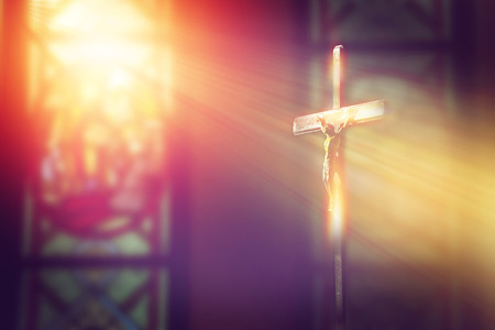 crucifix, jesus on the cross in church with ray of light from stained glassの写真素材