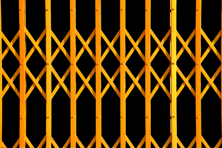 yellow geometric pattern from folding gate, ancient yellow expanded metal door on black backgroundの写真素材