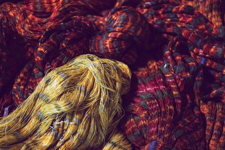 close up of red and yellow colour tie dye silk yarn for weaving, Thai mudmee fabric, silk yarn dyed...