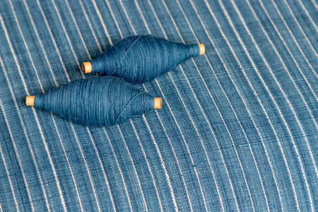 Indigo dyed yarn in reel and indigo dyed woven fabric backgroundの写真素材