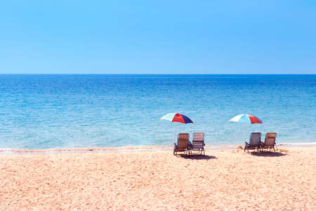 empty beach chairs on sand beach with blue sky and sea, no tourists on beach, empty summer in phuket...