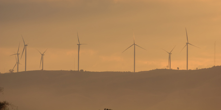 Wind turbines for electricity on a mountain at sunset.