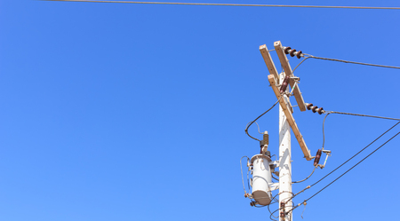 Electrical transformer on pole against a blue sky.