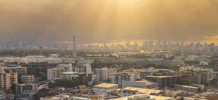 View of expanding city, changing environment. In the evening, the sun shines through cloudy sky and rain from the tower, The full-length landscape with buildings and architecture of Bangkok Thailand.の写真素材