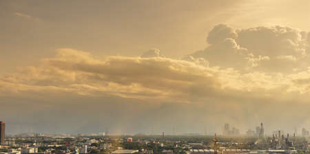 View of expanding city, changing environment. In the evening, the sun shines through cloudy sky and rain from the tower, The full-length landscape with buildings and architecture of Bangkok Thailand.の写真素材