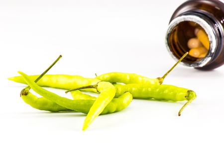 Green chilli with pill bottle on white isolation