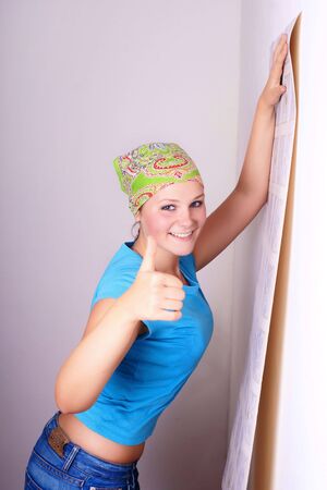 young woman tries on wall-papers to wall の写真素材