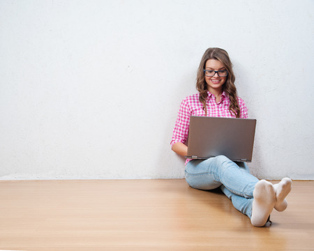Young creative woman sitting in the floor with laptop./ Casual blogger womanの写真素材