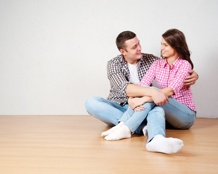 Portrait Of Happy Young Couple Sitting On Floor Looking Up Ready for your text or productの写真素材