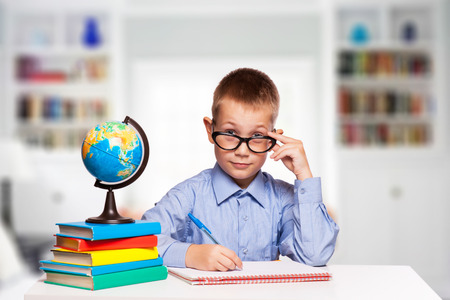 Cute schoolboy is writting isolated on a white background