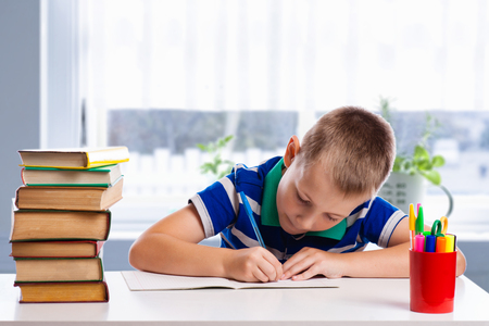 Cute schoolboy is writing isolated on a white backgroundの写真素材