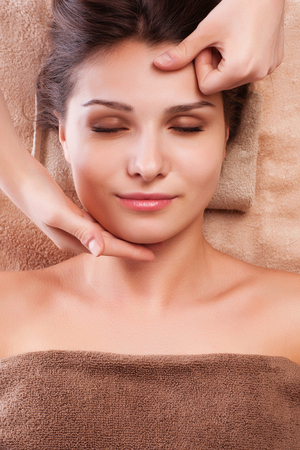 eautiful young relaxed woman enjoy receiving face massage at spa saloonの写真素材