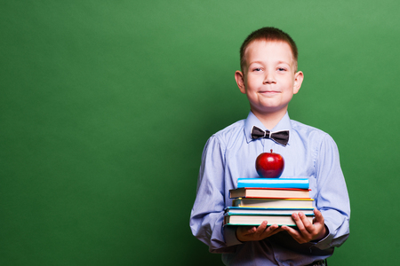 Happy little boy with books isolated on green backgroundの写真素材