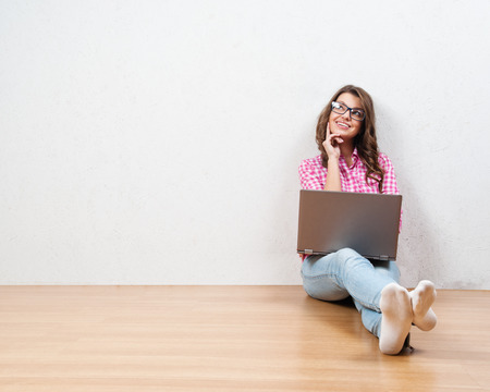 Young creative woman sitting in the floor with laptop./ Casual blogger womanの写真素材