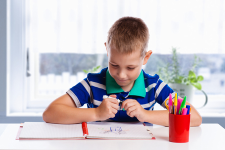 Happy cheerful child drawing with brush in album using a lot of painting tools. Creativity concept.の写真素材