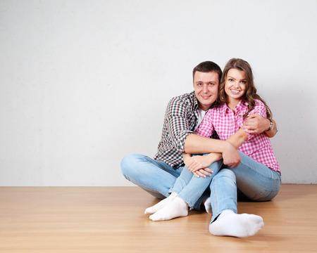 Portrait Of Happy Young Couple Sitting On Floor Looking Up Ready for your text or productの写真素材