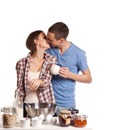 Affectionate man kissing his girlfriend while cutting bread for breakfast in the kitchenの写真素材