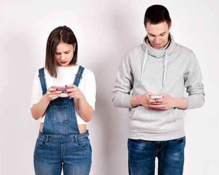 Divided young couple busy with their smartphones each.の写真素材