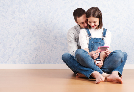 Shopping online together. Beautiful young loving couple shopping online while sitting on the floore together.の写真素材