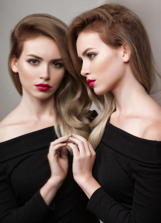 High fashion look.glamour fashion portrait of beautiful sexy brunette girl female model with bright makeup and red lips and her reflection in mirrorの写真素材