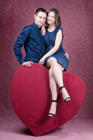 Young beautiful couple embracing in front of a huge heart.の写真素材
