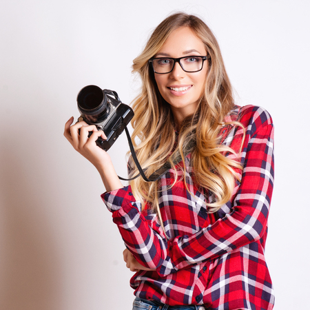 Woman photographer with camera against gray backgroundの写真素材