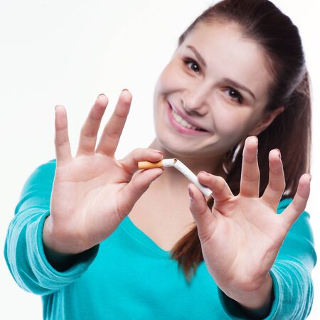 Young happy woman with broken cigarette. Stop smoking concept.の写真素材