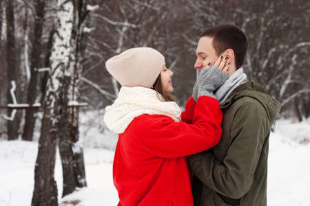 Embracing couple looking at camera with smiles in winter park.の写真素材