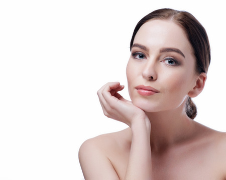 Beauty Woman Face closeup. Beautiful brunette young spa model girl with perfect skin. Skin care concept. Fresh Clean Skin. Portrait of female looking at camera and smiling. Beige background.の写真素材