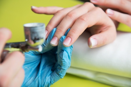 Closeup shot of a woman in a nail salon receiving a manicure by a beautician with nail file. Woman getting nail manicure. Beautician file nails to a customer.の写真素材