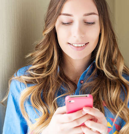 Happy hipster girl texting on a smart phone. Natural portrait.の写真素材