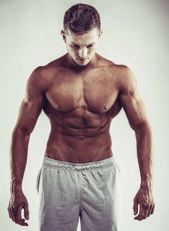 Sport concept. Close up image of muscular caucasian male in sports clothing over grey background.の写真素材