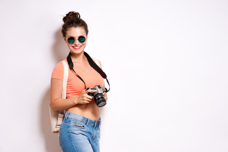 Happy young hipster woman in glasses holds retro photo camera.の写真素材