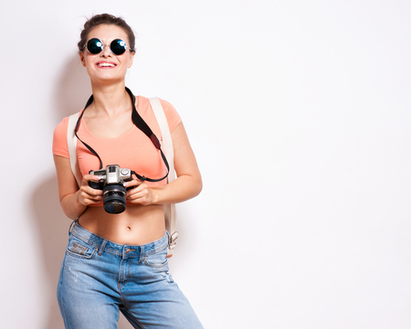 Happy young hipster woman in glasses holds retro photo camera.の写真素材