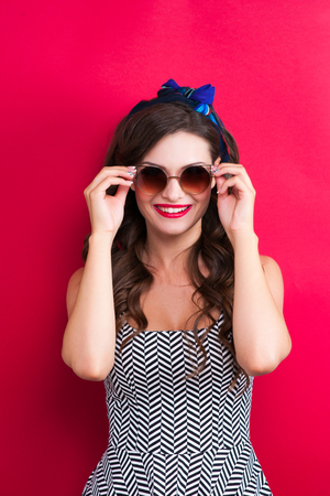 Beautiful young sexy pin-up girl with surprised expression, on red background.の写真素材
