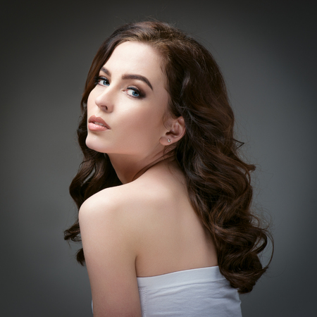 Beautiful girl with long wavy hair . Brunette with curly hairstyleの写真素材