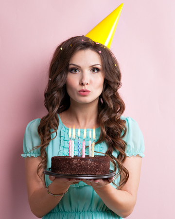 Woman blows out the candles on a birthday cake.の写真素材