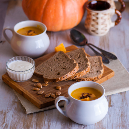 Roasted pumpkin and carrot soup with cream and pumpkin seeds on white wooden background. Copy space.の写真素材