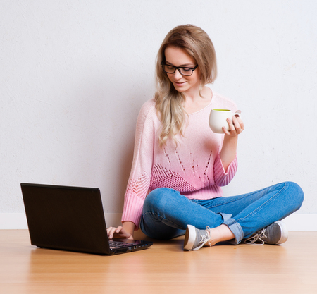 Young creative woman sitting in the floor with laptop. Casual blogger womanの写真素材