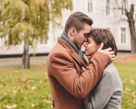 Young couple in love holding hands and walking through a park on a sunny autumn day.の写真素材