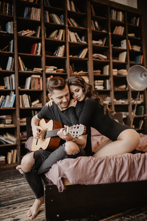 beautiful sexy girl and her boyfriend playing guitar.の写真素材