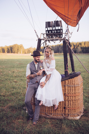 Lovely young couple in wedding dresses in Bohho style, on a field with a balloon.の写真素材