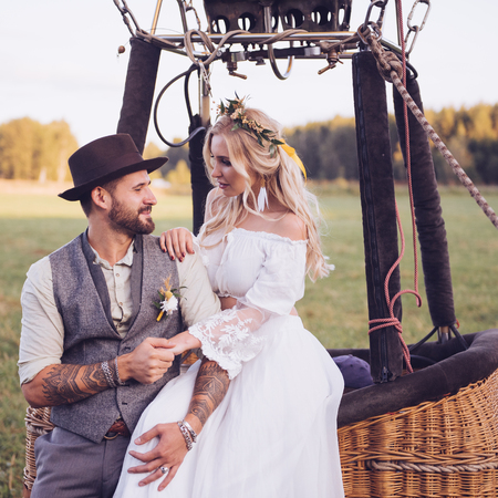 Lovely young couple in wedding dresses in Bohho style, on a field with a balloon.の写真素材