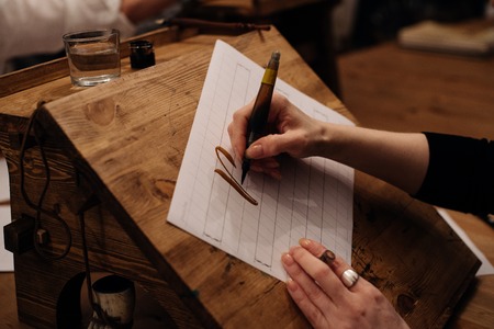 View on big sheet of white paper canvas with word calligraphy spelled on top using brush with black ink by font designer or creative artist freelancer working on project in home studio.の写真素材