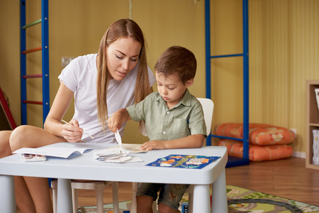 Mother and son draw at a table inside the room.の写真素材