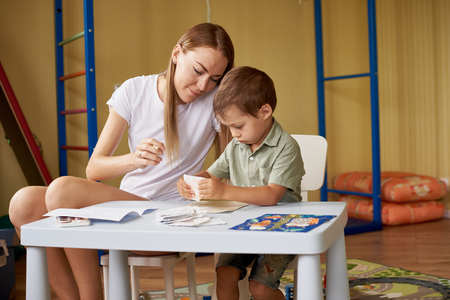 Mother and son draw at a table inside the room.の写真素材