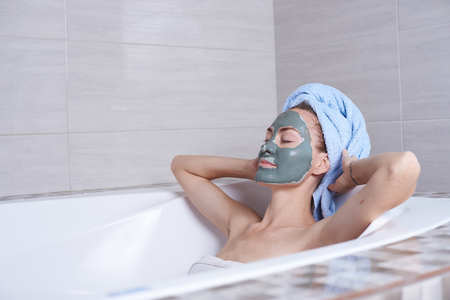 Portrait of a woman in facial alginate mask lying in the retro bath in the bathroom.の写真素材