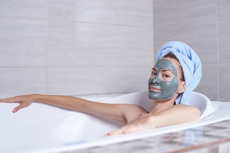 Portrait of a woman in facial alginate mask lying in the retro bath in the bathroom.の写真素材